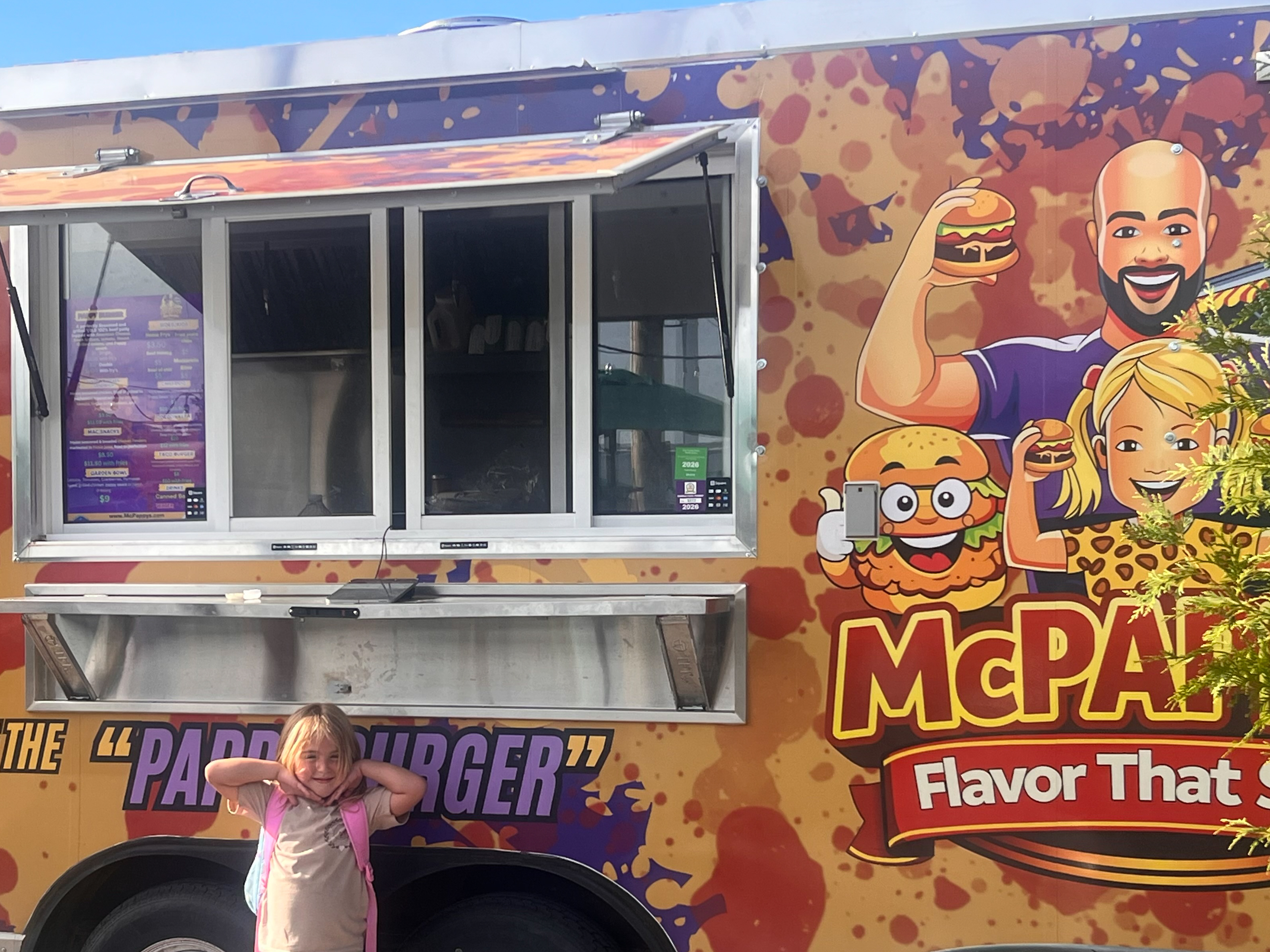 McPappy's friendly staff smiling at the camera through the food truck window
