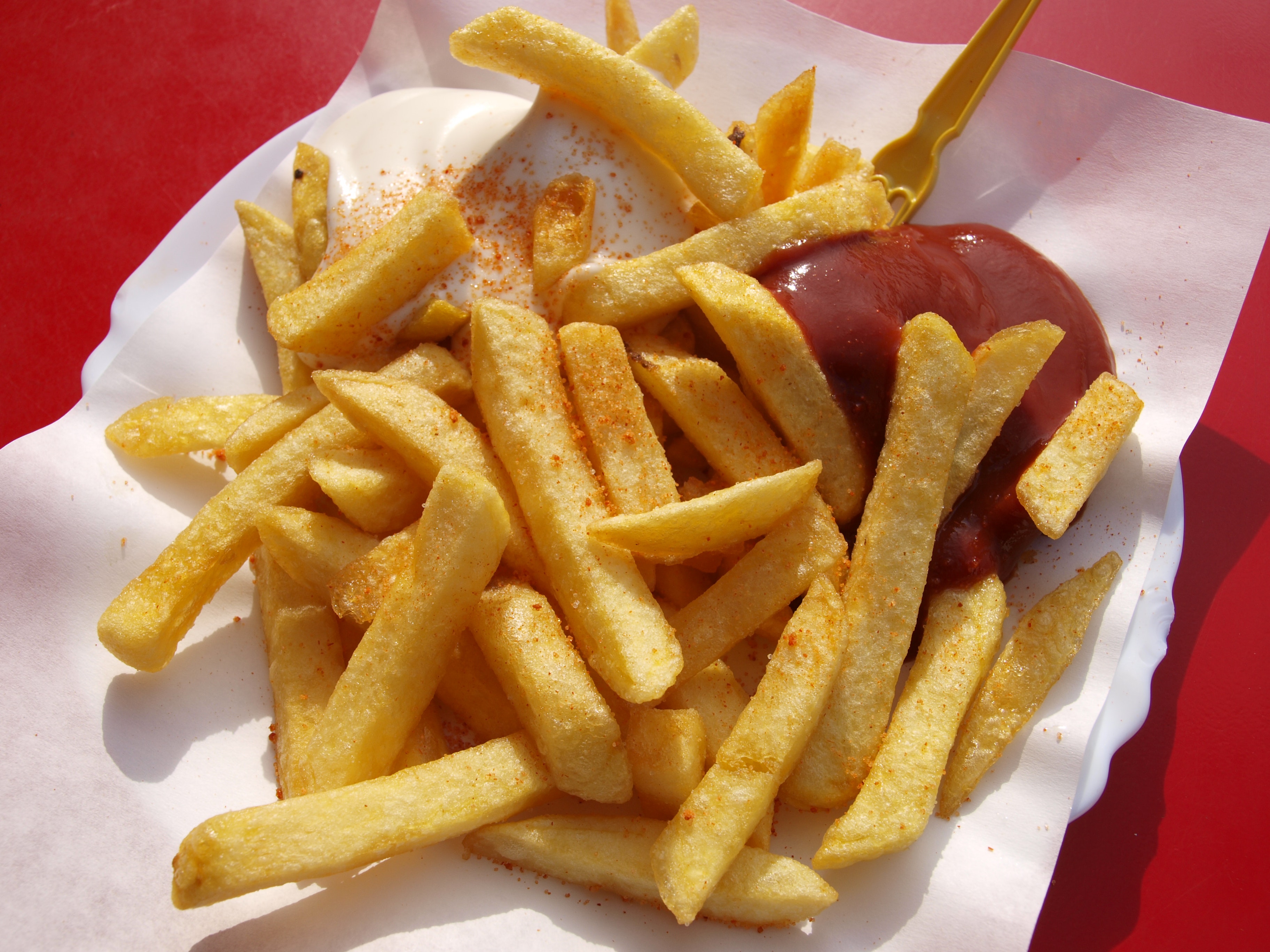 Closeup photo of tasty seasoned French Fries laying around and in a little bit of ketchup